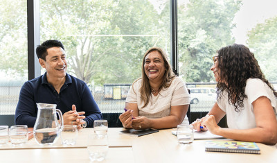 Three business people at a table laughing.