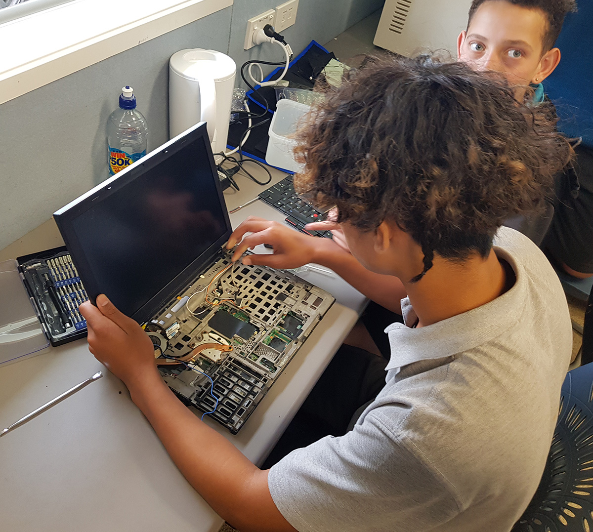Image of two young children looking at the inside of a computer