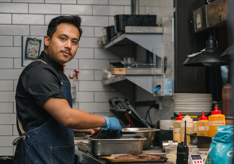 Male migrant worker preparing meat in a commercial kitchen