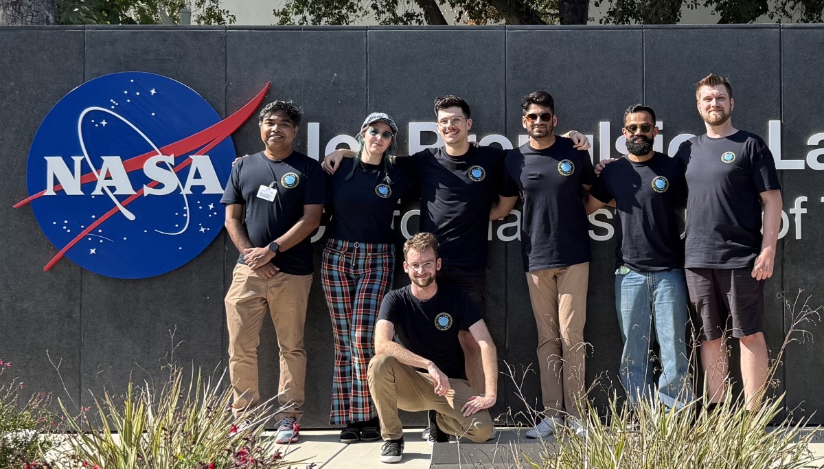 Photo of the 7 recipients of the 2025 New Zealand Space Scholarship standing in front of a sign with the NASA logo. The people are obscuring the words behind, which are Jet Propulsion Laboratory, California Institute of Technology.