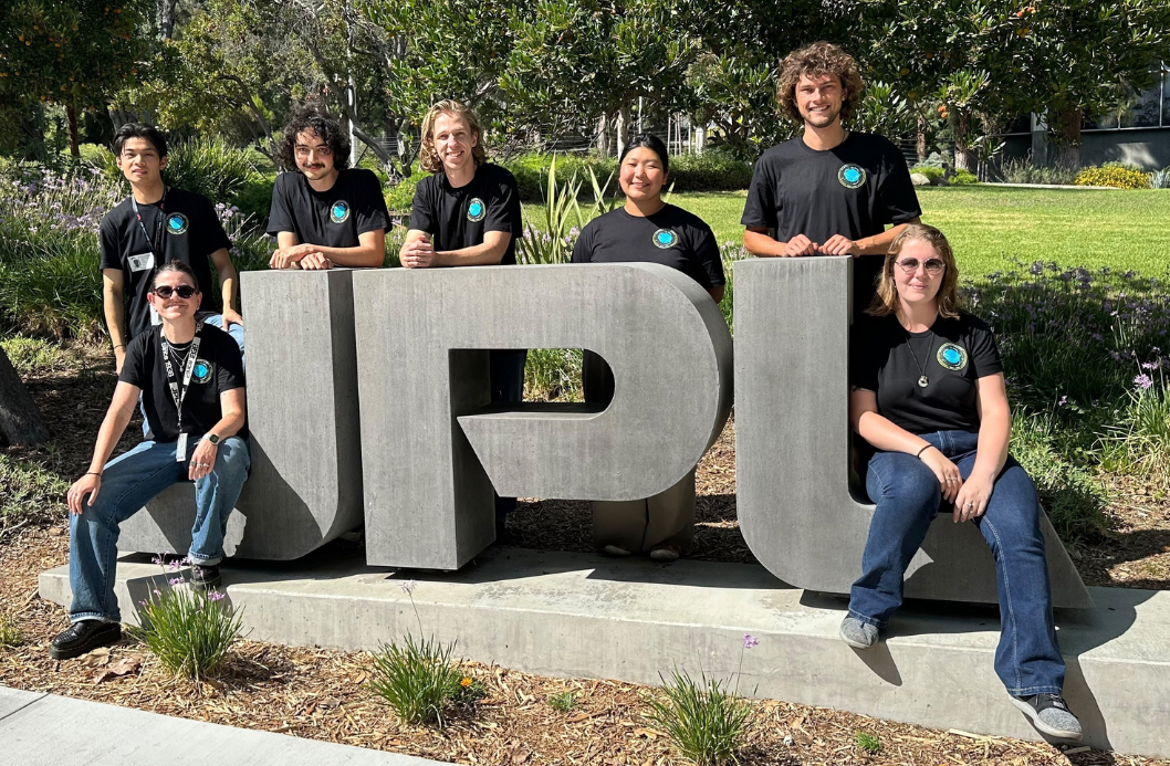 2026 New Zealand Space Scholarship recipients with the Jet Propulsion Laboratory campus statue 'IPL' in concrete.