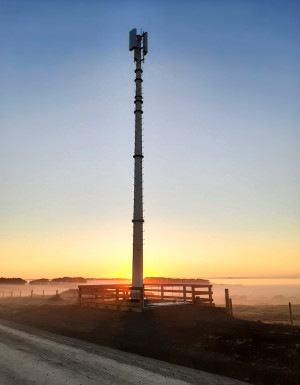 A mobile tower with the sun rising in the background.