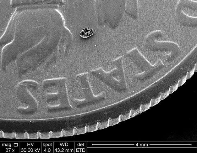 ’Benchy’ the tugboat, approximately the size of a grain of sand, sitting on a US dime.