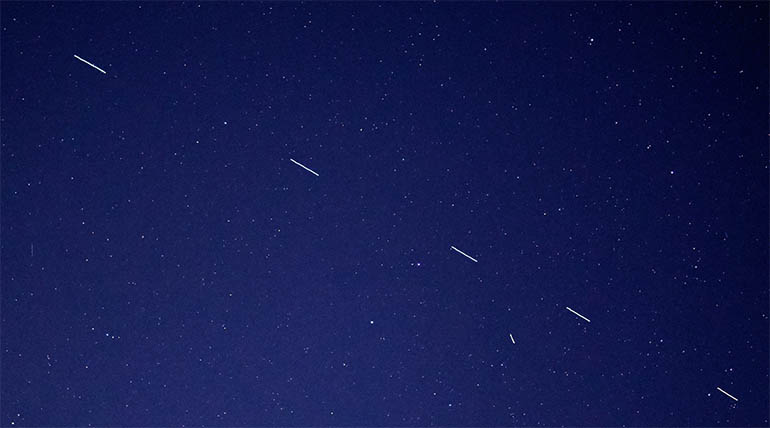 A satellite internet constellation transiting the night sky over the Pacific coast of California in 2019.