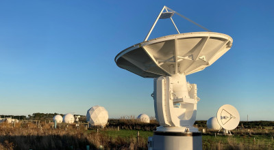 Photo of a ground station, with a radio dish in the foreground