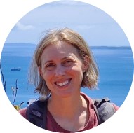 Cristina Parigini smiling outside with an ocean in the background.