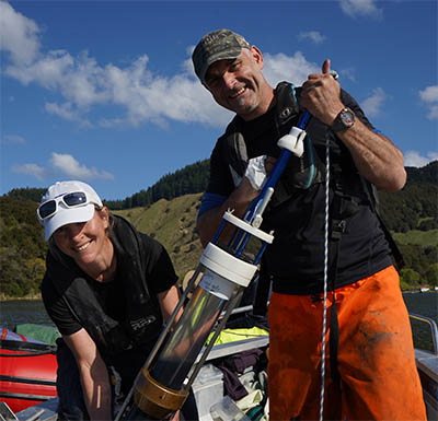 Two researchers on a boat, holding a piece of science technology used in the Lakes380 study.
