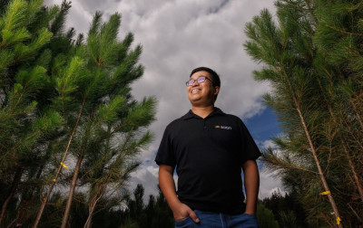 Smiling person standing in a pine forest