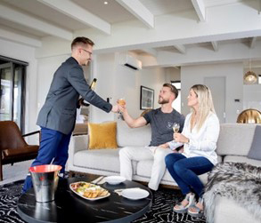 Two guests being served wine by a waiter in a lounge area.