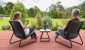 Julie and Jonathan from Ribbonwood Retreat sitting on a deck drinking red wine.