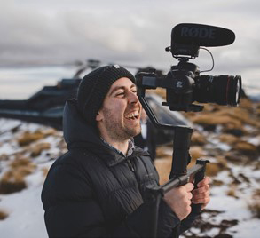 Scott from Wild In White standing in a snowy mountainous place with his camera.