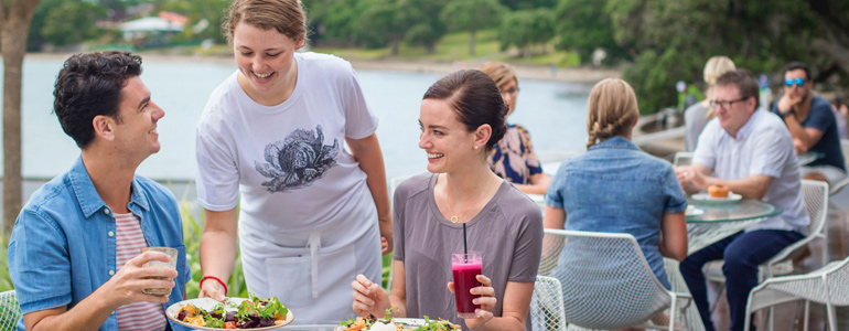 Couple being served at an outdoor restaurant by a smiling server