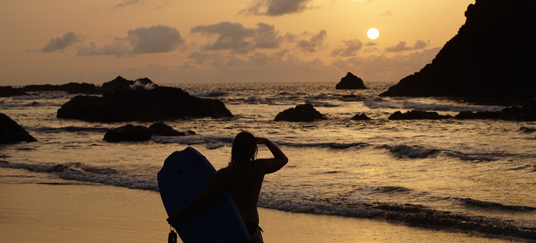 Body boarder at the beach at sunset looking out at the water