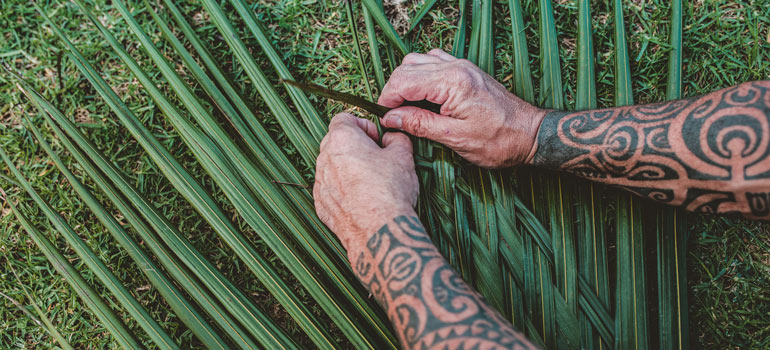 hands weaving flax bush