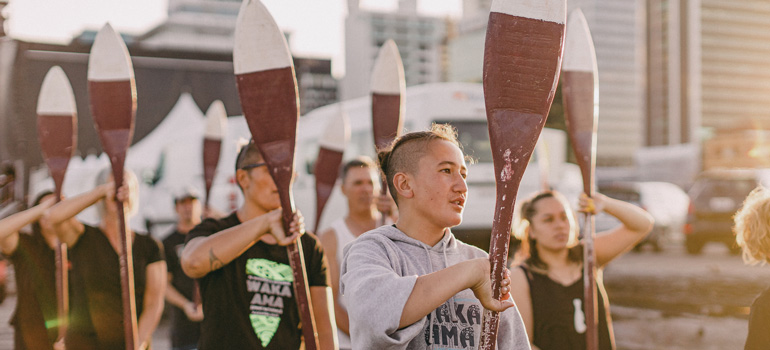 people practicing waka ama holding oars in the air 770x350