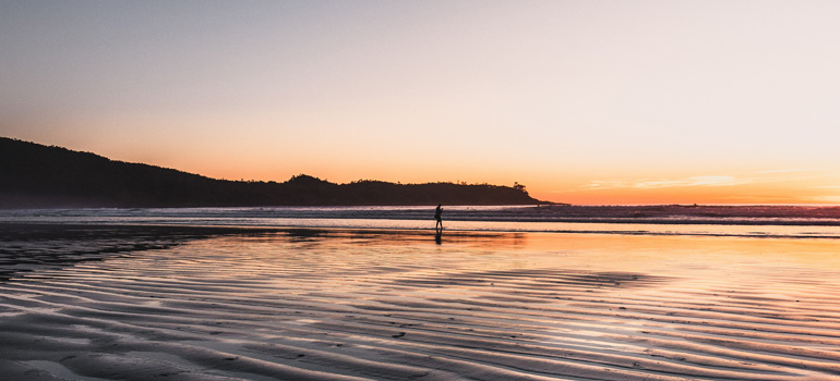 Person walking on beach at sunset