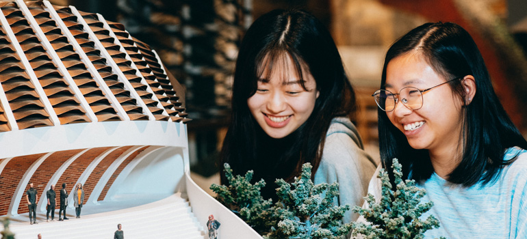 two people looking at miniature model 770x350