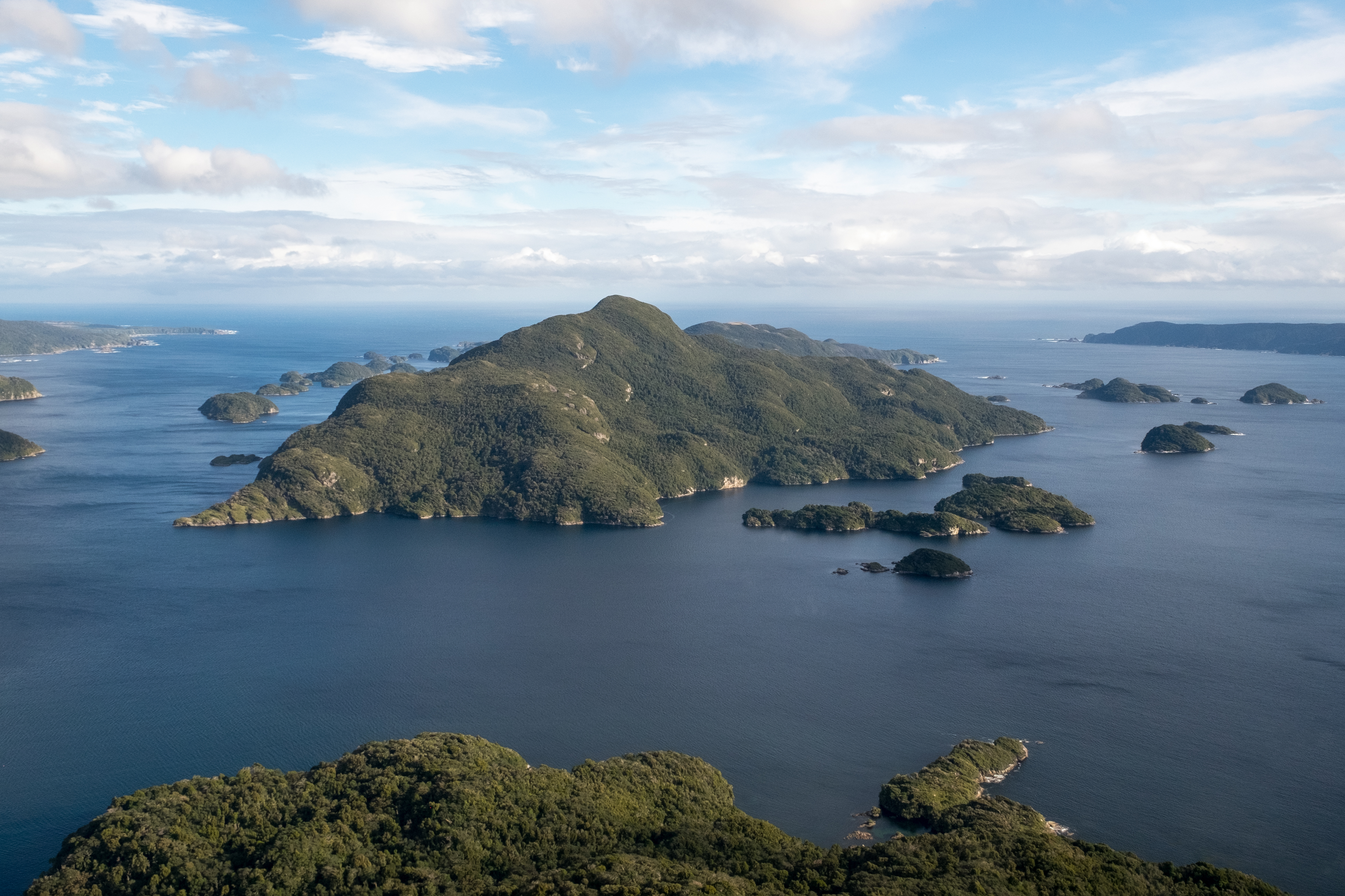 Landscape picture of Anchor Island and surrounding sea during daylight hours with patchy cloud cover.