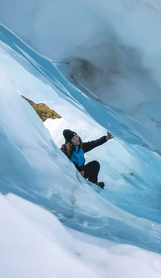A woman exploring huge valleys of ice at Fox Glacier. 