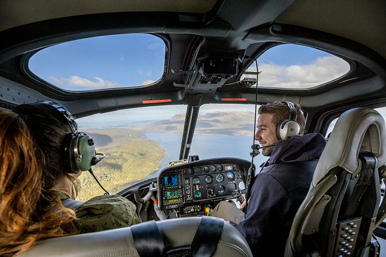 2 people in a helicopter looking at spectacular aerial views of Rotorua.