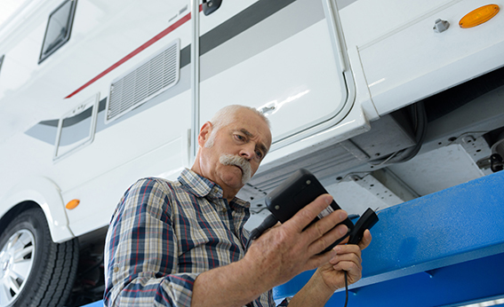 A mature auto mechanic at work on a campervan